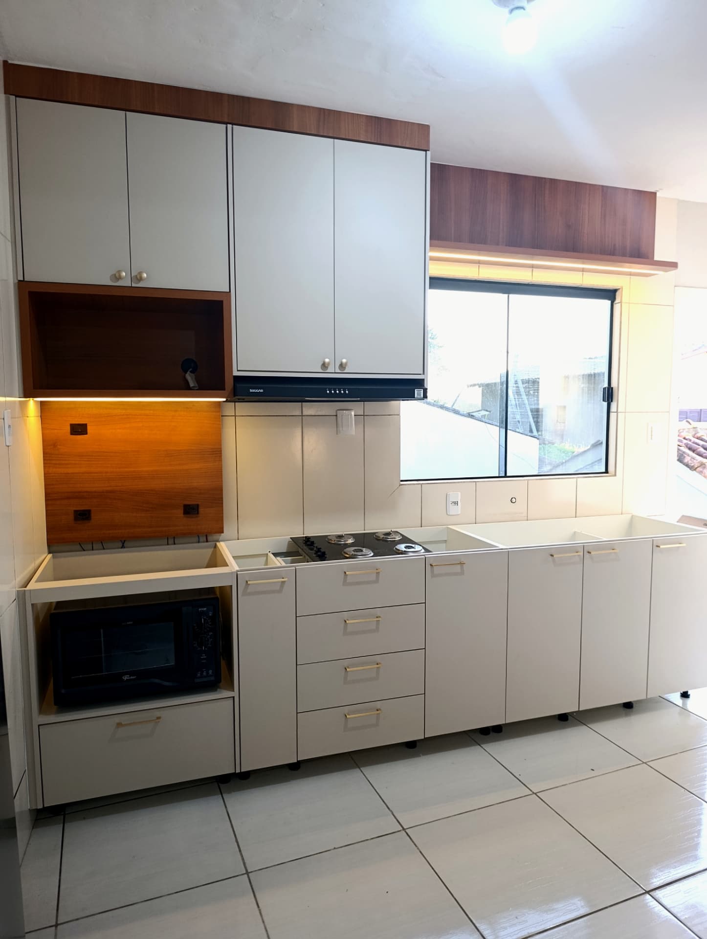 Cozinha planejada clara com detalhes em madeira e armários sob a janela